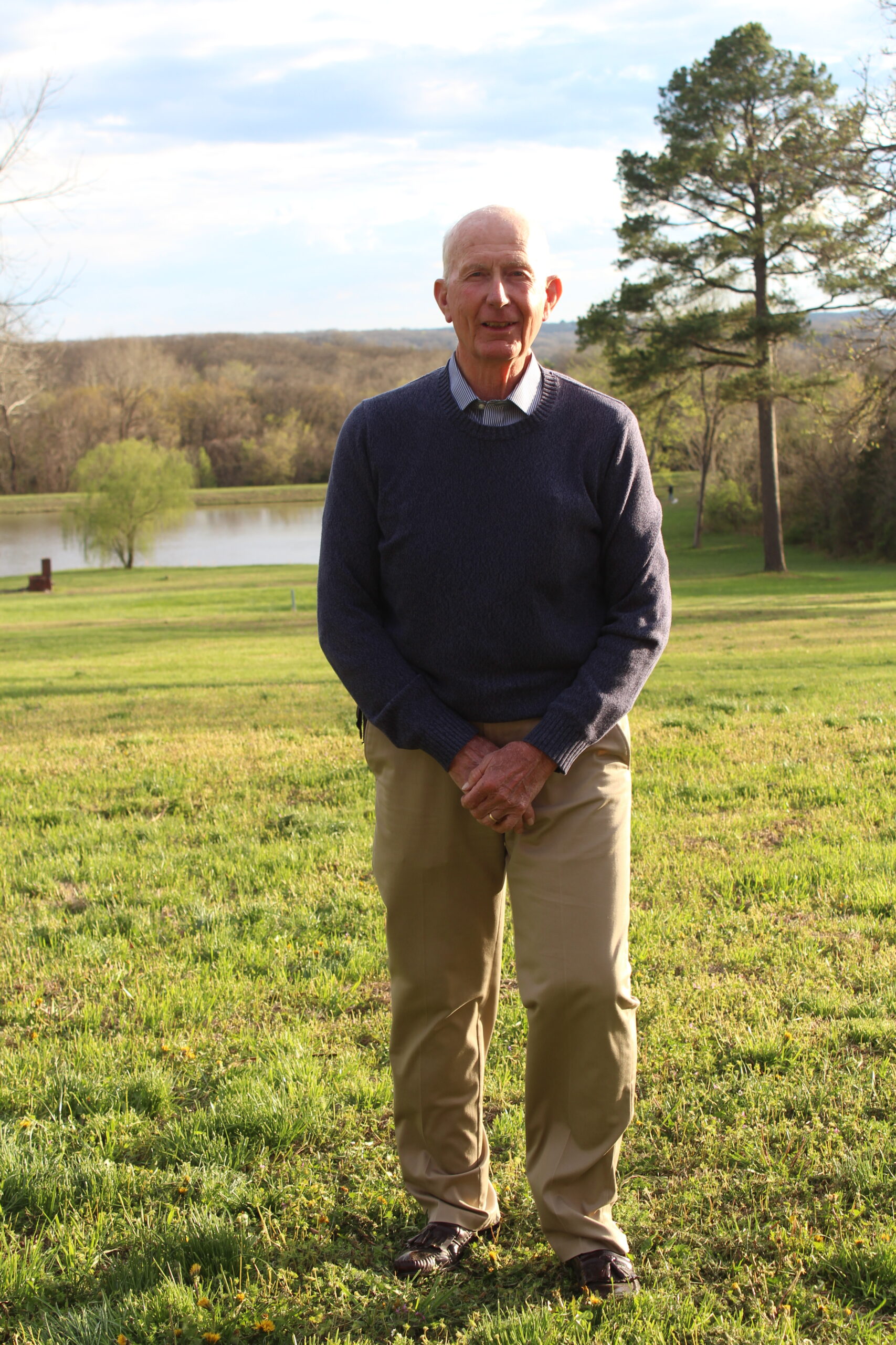 Staff member stands on lawn near a lake.