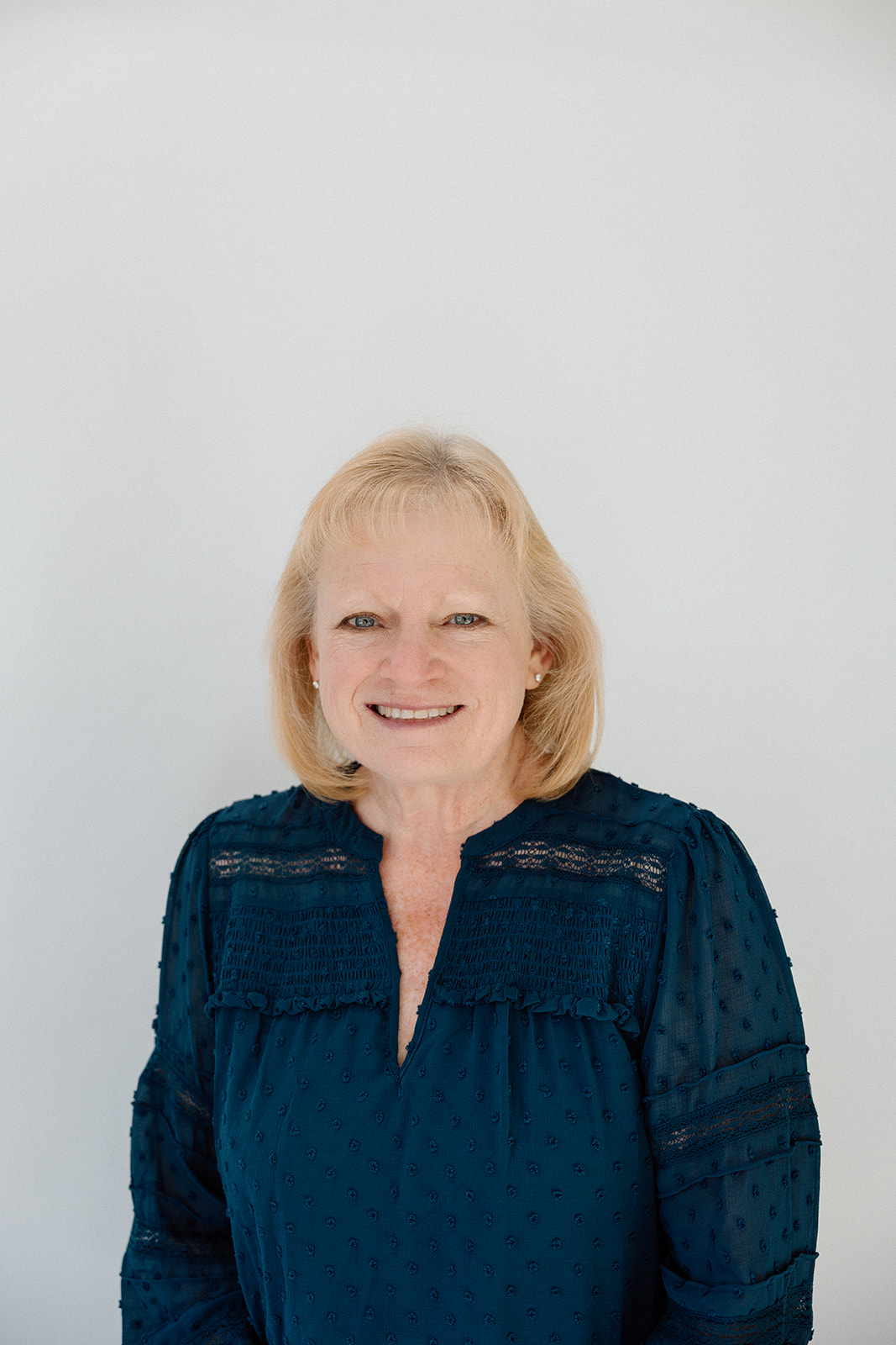 Portrait of a blonde woman in a blue blouse, likely discussing leadership and staff.