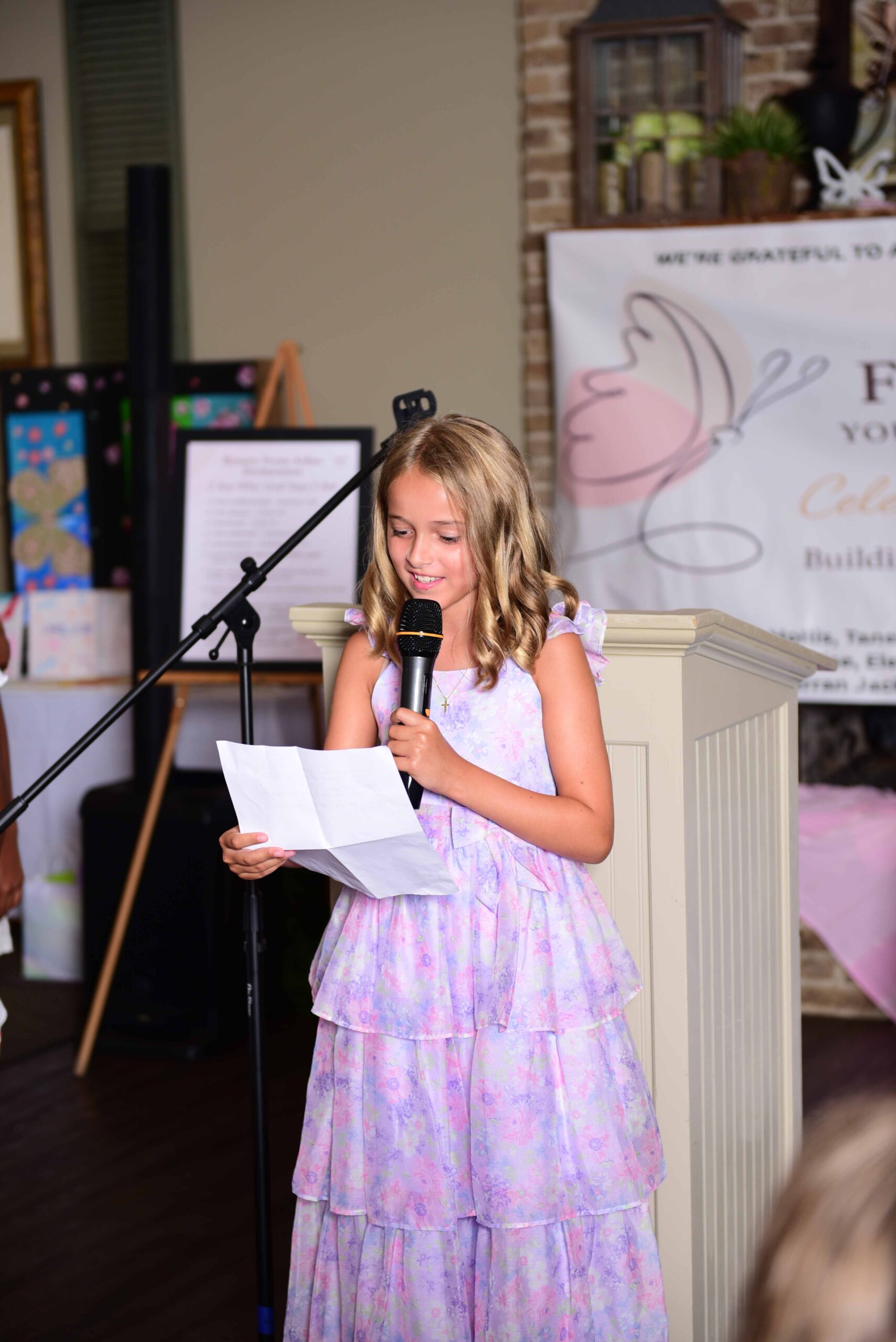 Girl in dress giving speech at Beauty From Ashes Youth Leadership Academy event.