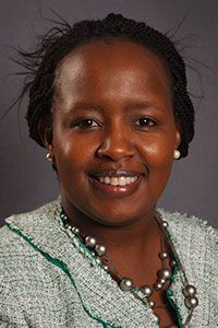 Headshot of Dr. Joy Mwenda smiling, wearing a patterned jacket and pearl necklace.