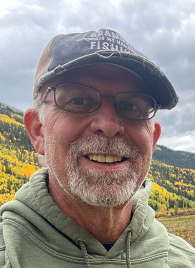 Bob Bonnar smiling outdoors, wearing a fishing hat. Hat reads: