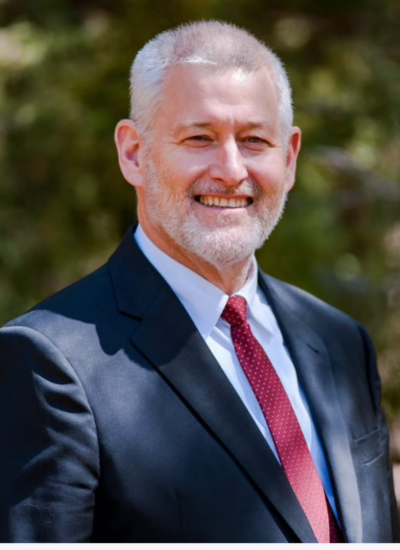 Brian D. Schroeder Sr. in a suit and tie smiles at the camera.