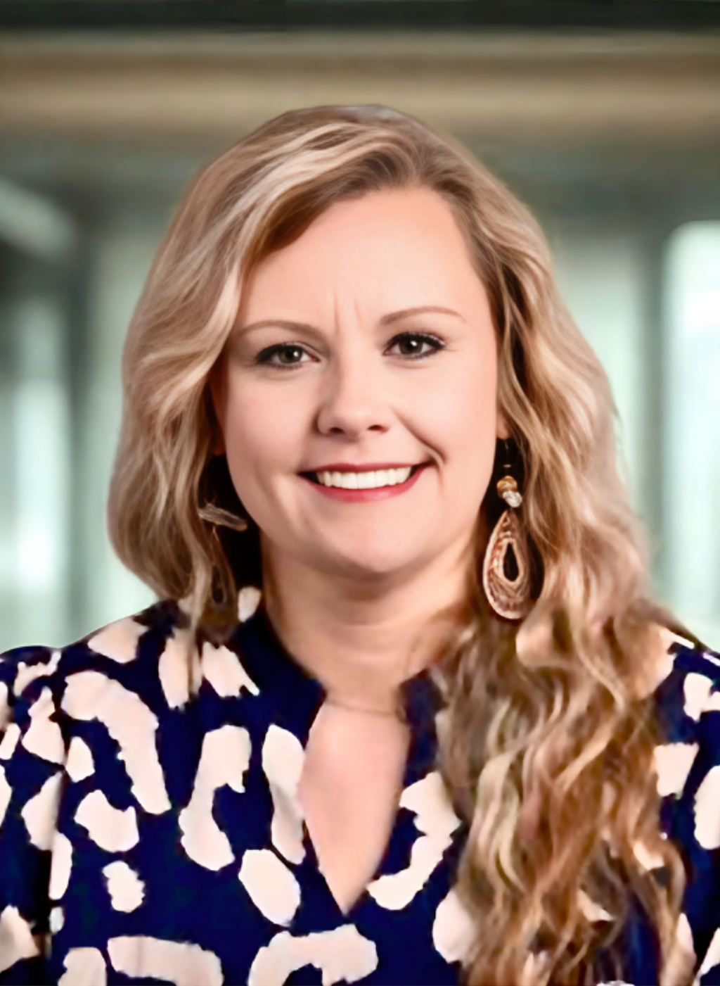 Robyn Smith, smiling woman with blonde hair wearing a patterned blouse and earrings.