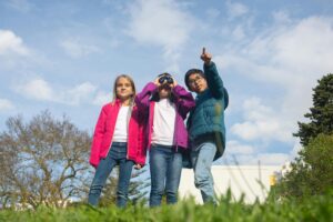 Kids using binoculars and pointing outdoors. Upcoming events at Trellis Academy.