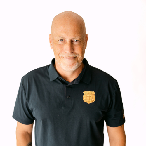 Ken Steen, a bald man in a dark polo shirt with a crest, smiling