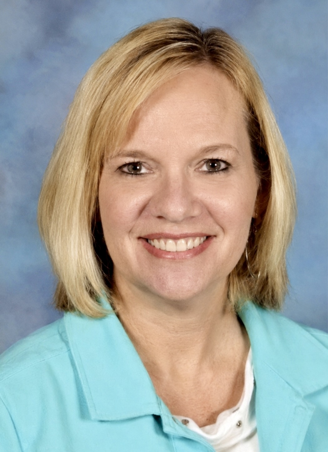 Beth Curry, a smiling woman with blonde hair, wearing a turquoise shirt.