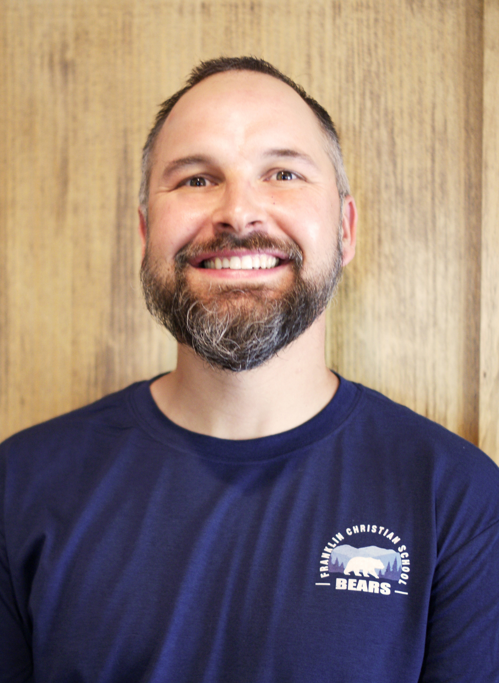 Seth Stradling, Franklin Christian School Bears coach, smiles in a navy t-shirt.