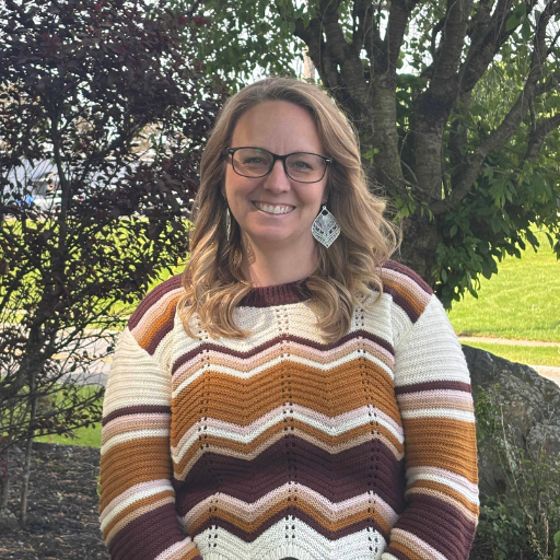 Laura Claggett in brown and white striped sweater smiling in outdoor setting